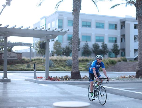 Viasat employee riding his bike across the crosswalk at the corporate Carlsbad campus